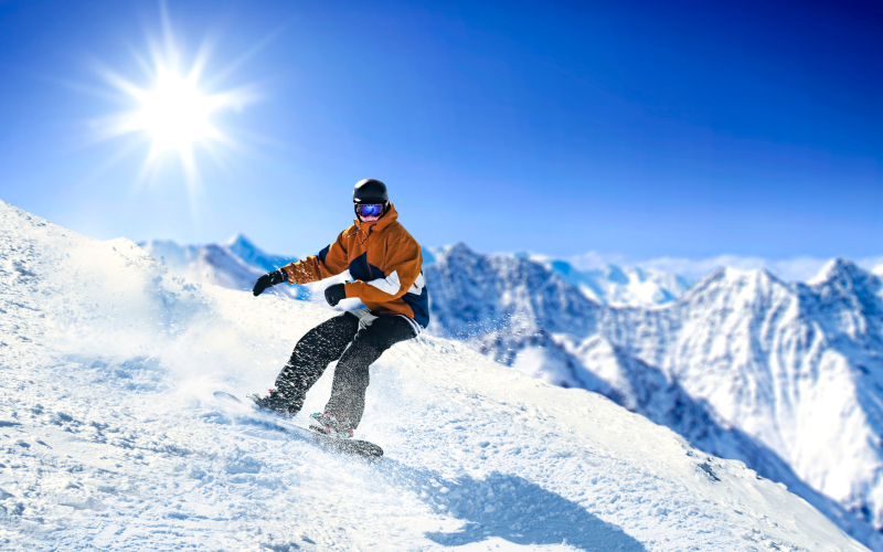 man met snowboard glijdt van de piste op een zonnige dag
