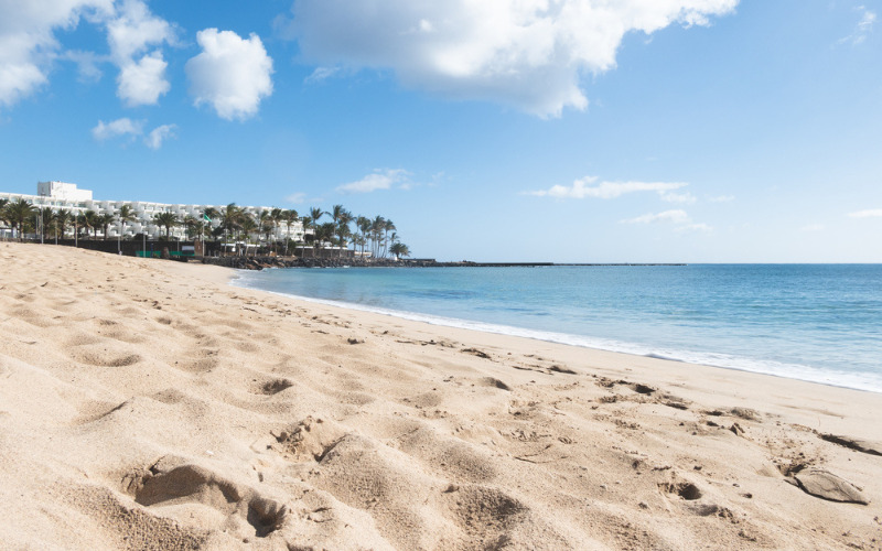 Plage de sable fin, avec hôtels blancs et palmiers au vent, Costa Teguise, Lanzarote, Espagne