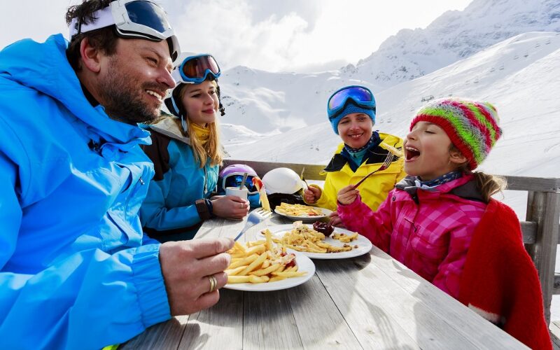 Une famille partageant un repas en terrasse au ski