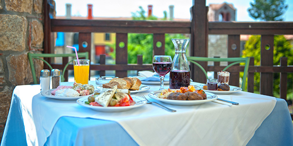Gedekte tafel met borden met eten, glas wijn en glas met sinaassappelsap.