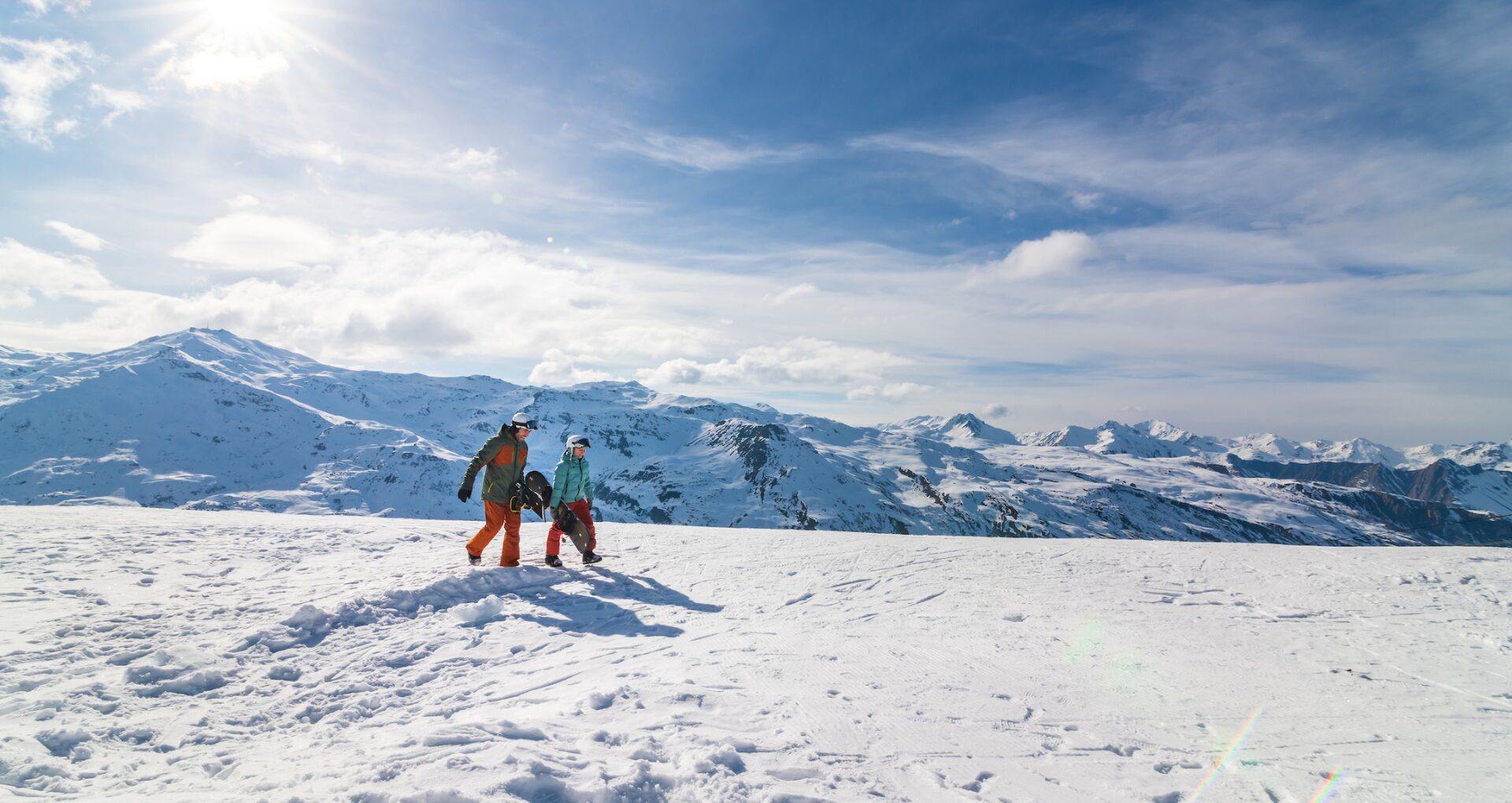 Deux skieurs marchant sur les pistes de ski, avec les montagnes enneigées en arrière-plan