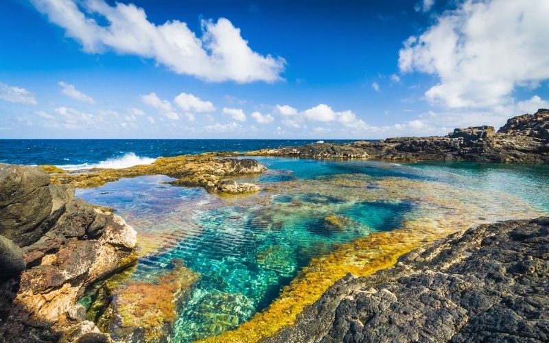 Uitzicht over een helderblauwe zee en een natuurlijk zwembad van rotsen op Lanzarote. 