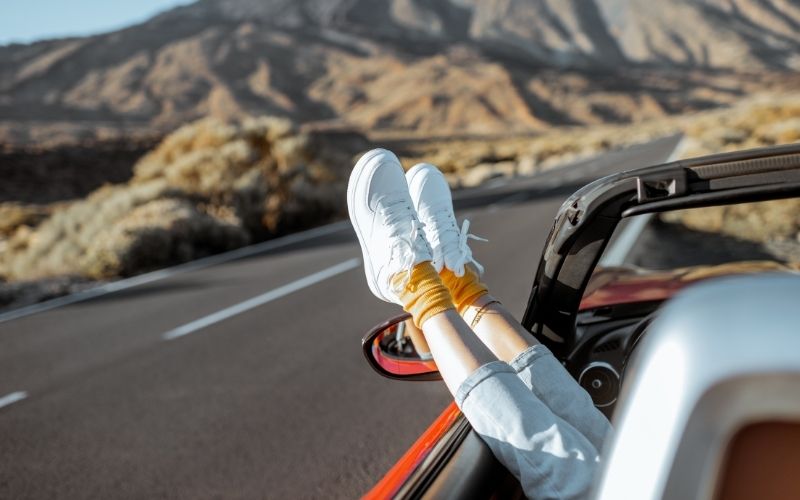 Vrouw steekt voeten uit het open dak van haar auto op Tenerife
