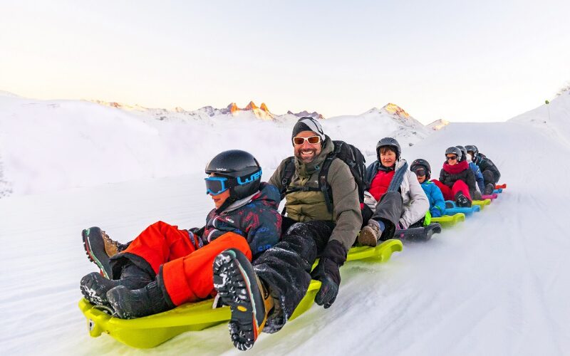 Une famille au ski faisant de la luge sur une piste de ski 