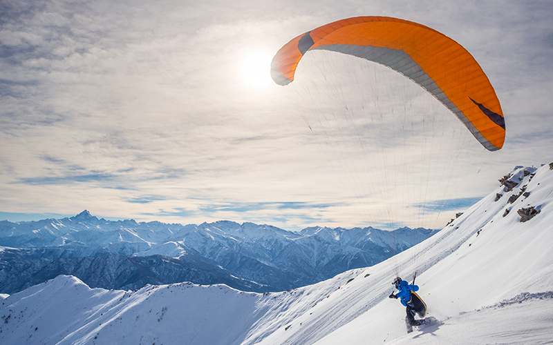 Parapente sur les pistes de ski avec les montagnes enneigées en arrière-plan