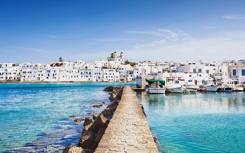 Pier richting Grieks vissersdorp, Paros, Griekenland aan helderblauwe zee en witte huisjes