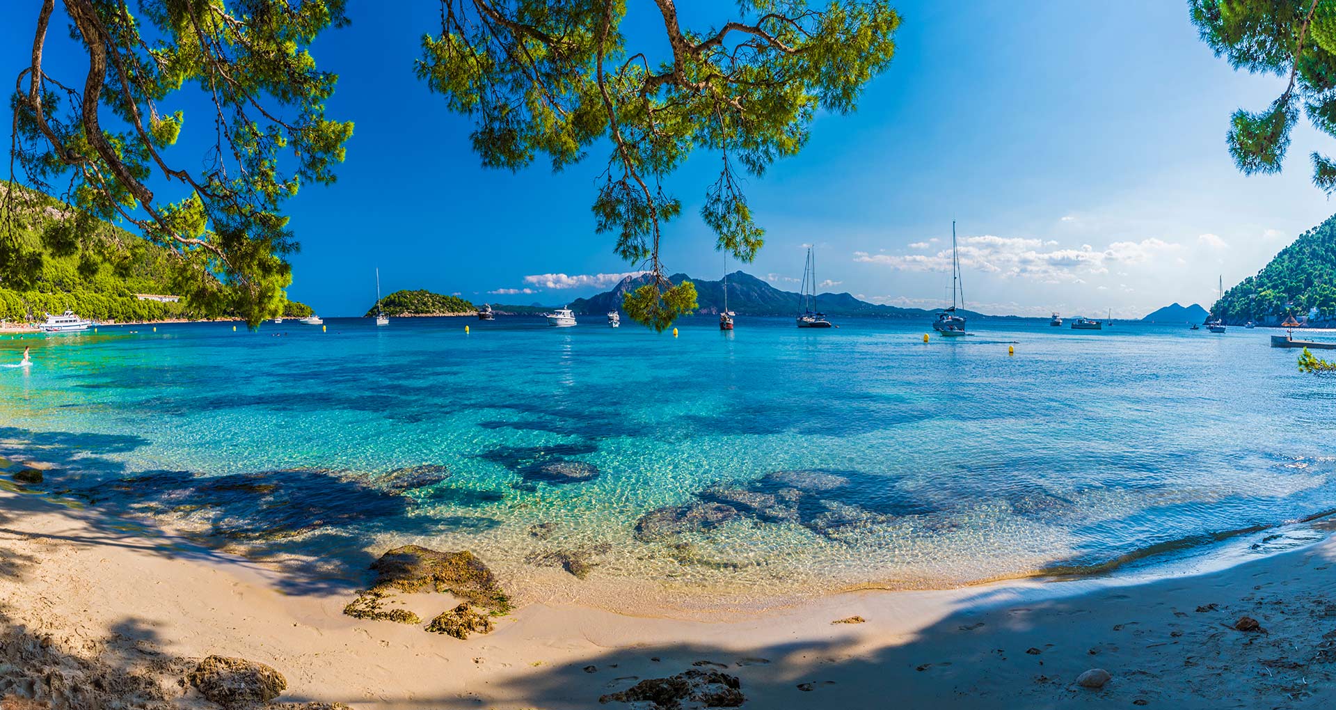 Uitzicht over de zee bij Mallorca met boten varend op het heldere blauwe water.