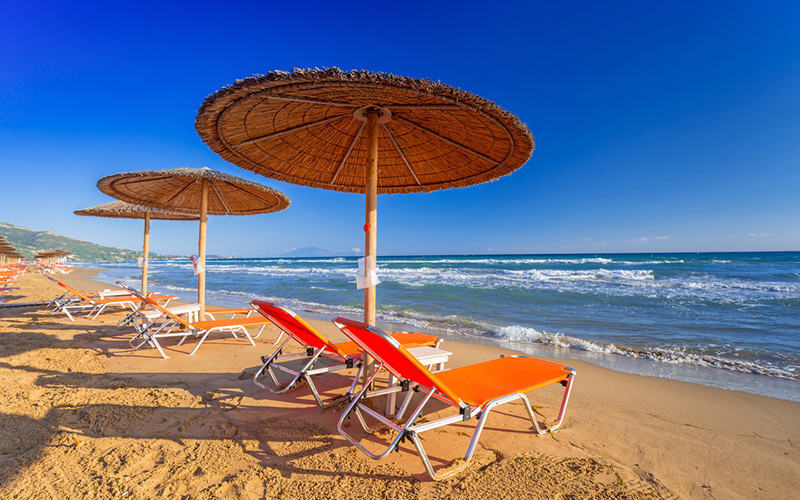 Strand met oranje ligbedden en rieten parasols