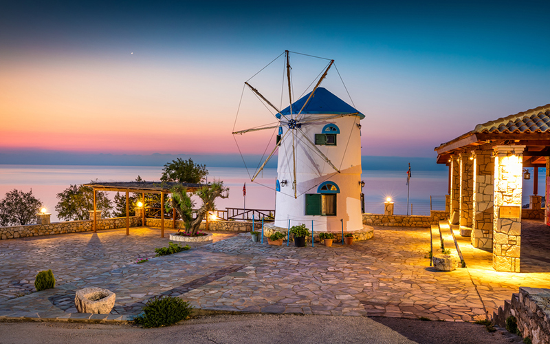 Oude windmolen aan de zee bij zonsondergang