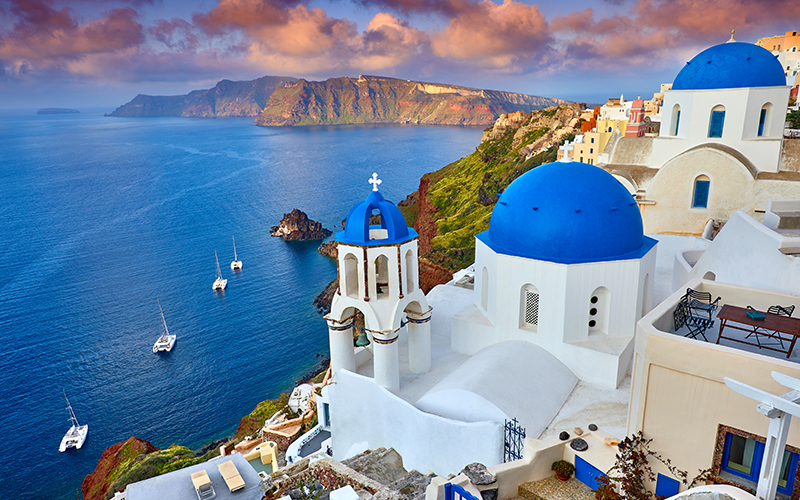 Griekse witte huisjes met blauwe daken van bovenaf gezien met op de achtergrond de zee