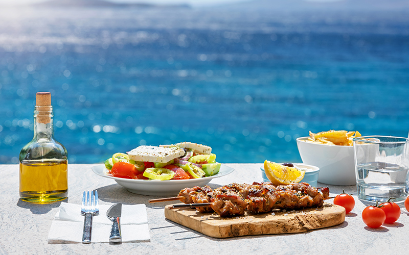 gedekte tafel met gyros en griekse salade met uitzicht op zee 