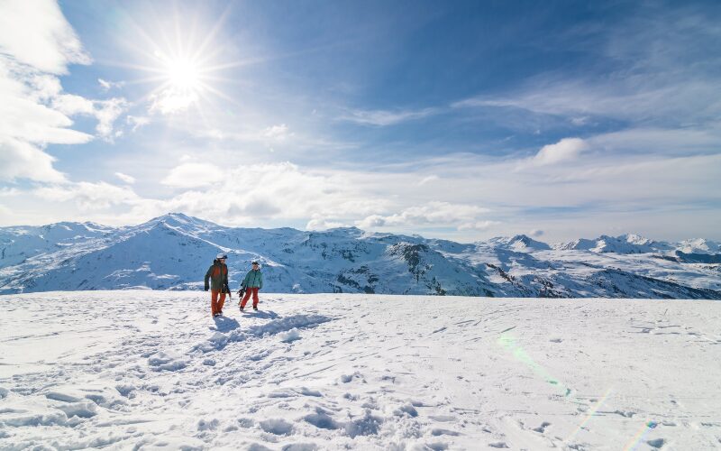 Deux skieurs marchant sur les pistes ensoleillées des Menuires