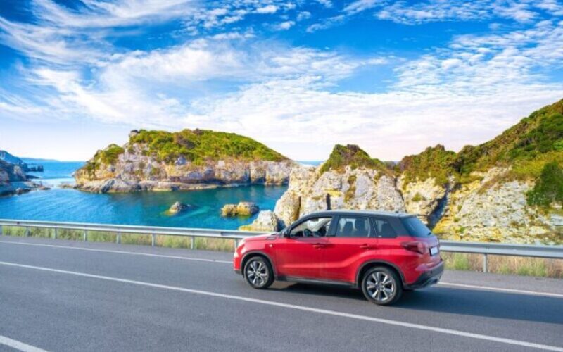 Voiture rouge avec en arrière plan paysages et falaises