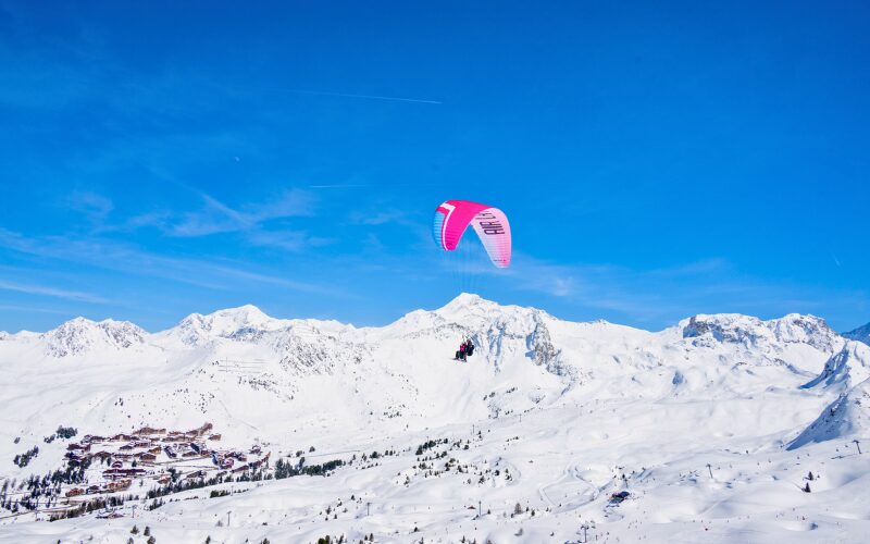 Un homme faisant du parapente au-dessus des montagnes de La Plagne