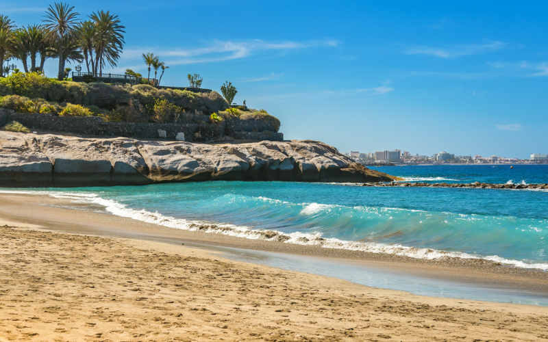 Un regard pittoresque sur Playa Del Duque à Ténérife, avec une large plage de sable et des eaux turquoise tranquilles